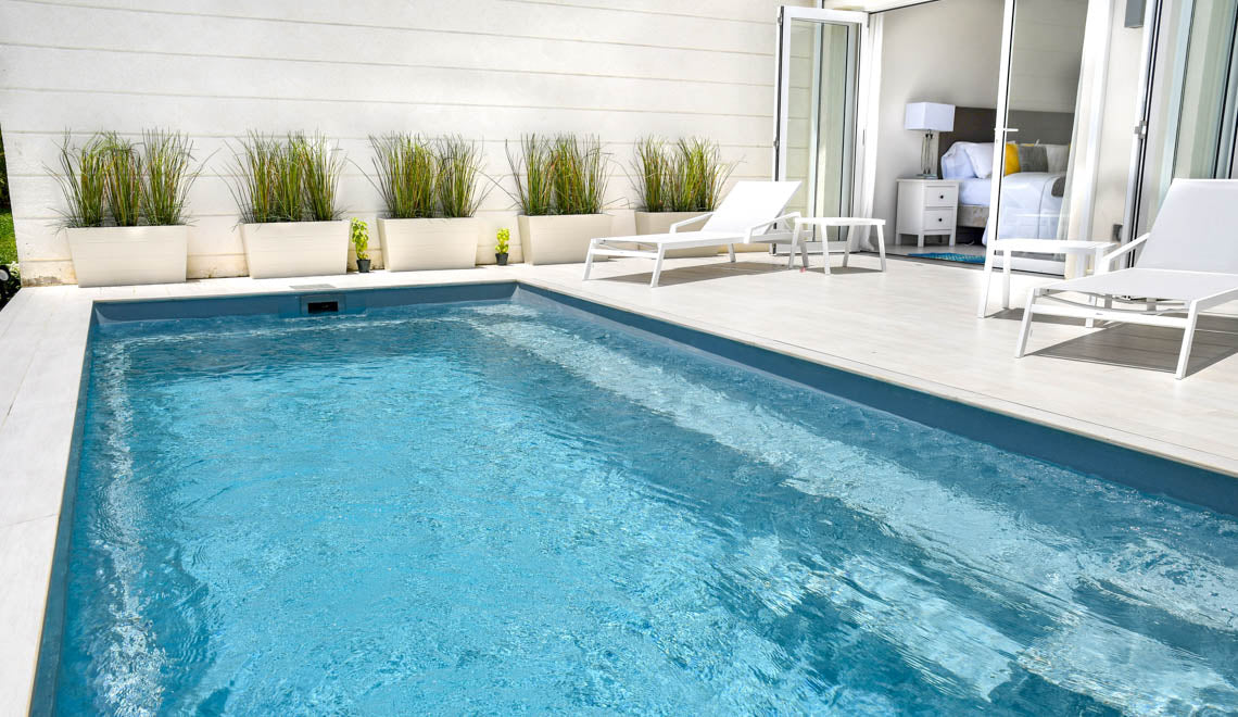 Leisurepools Harmony rektangulär pool med klart blått vatten och ljus betongkant